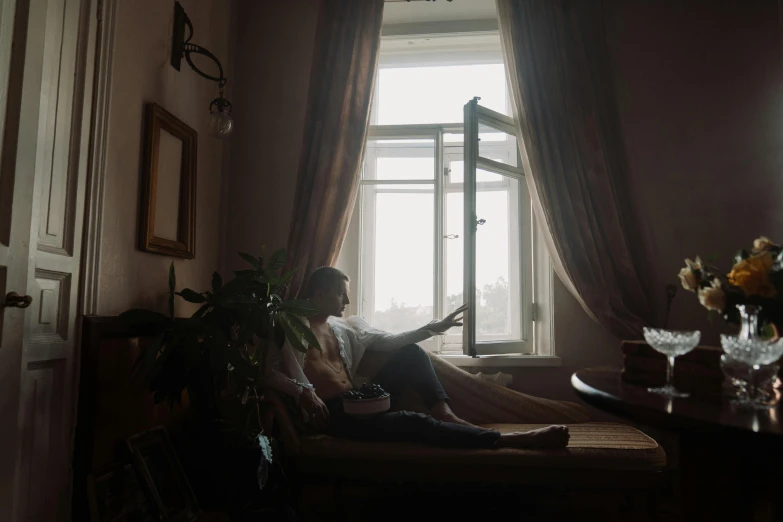 a man sitting on a couch in front of a window