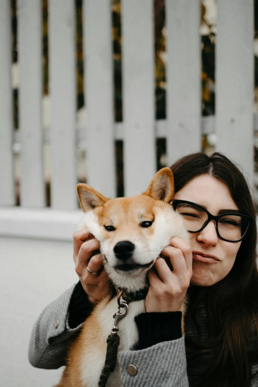 a woman in glasses holding a puppy on a leash