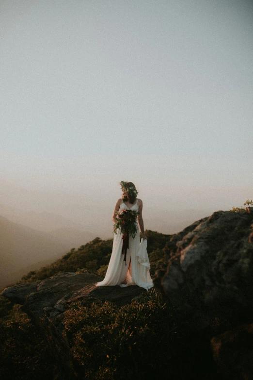 the bride at the top of the mountain takes a picture