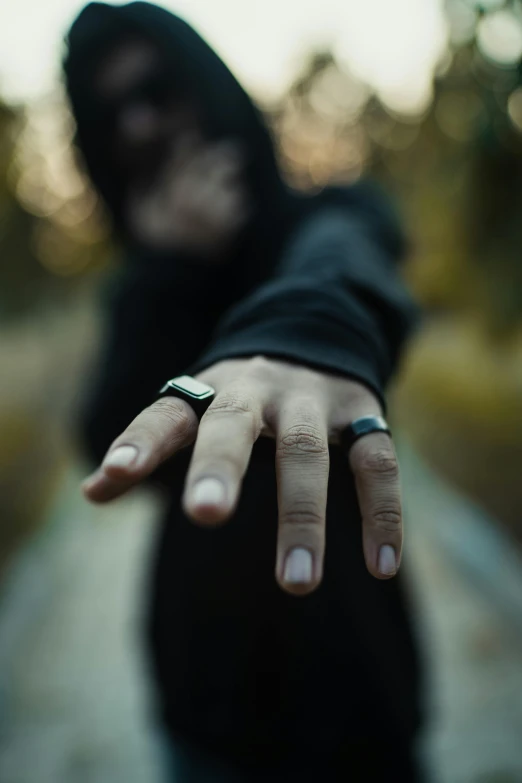 a person wearing a hood and a ring holding the end of their arm