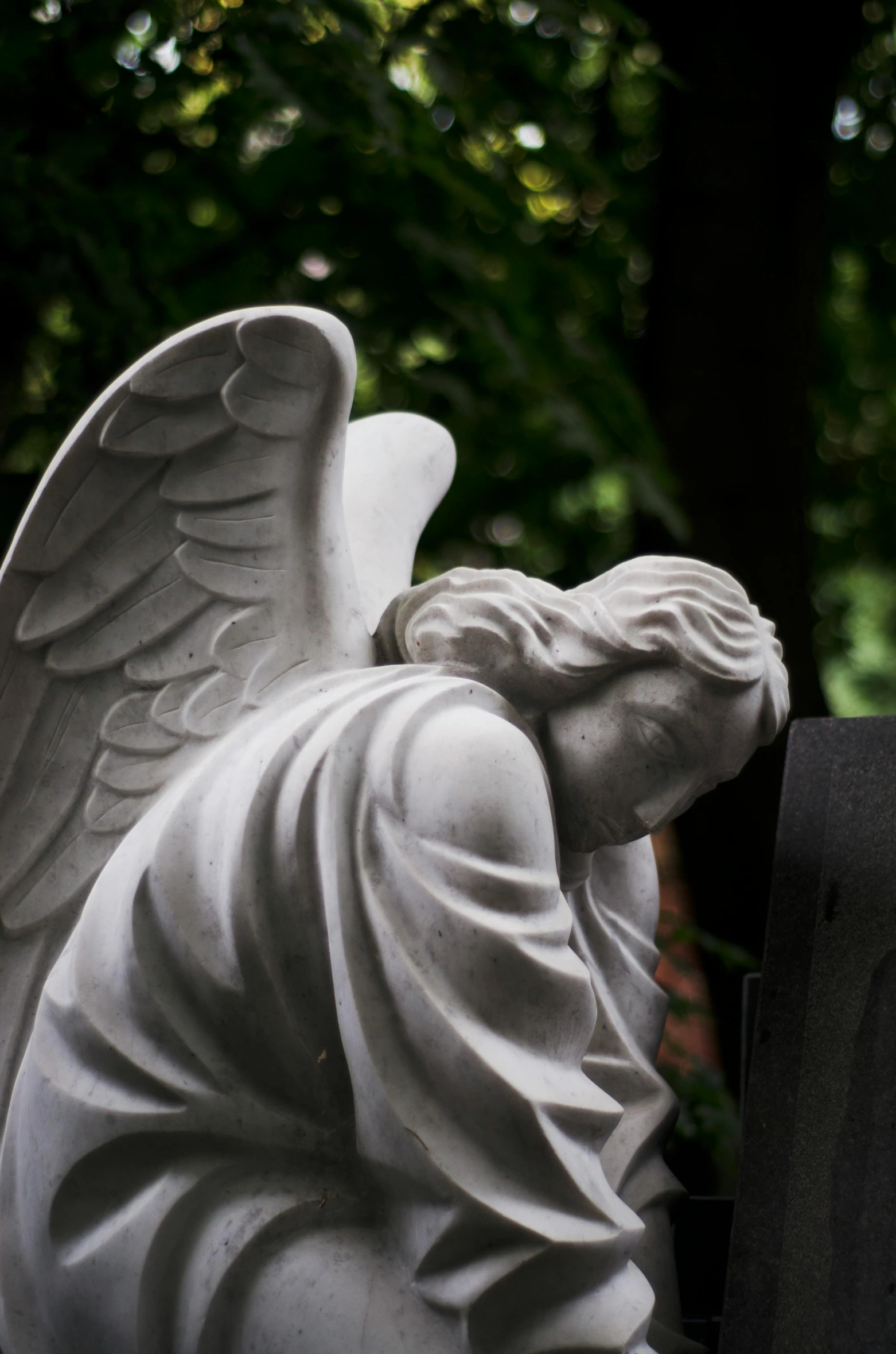 statue of a fallen angel holding a black bird