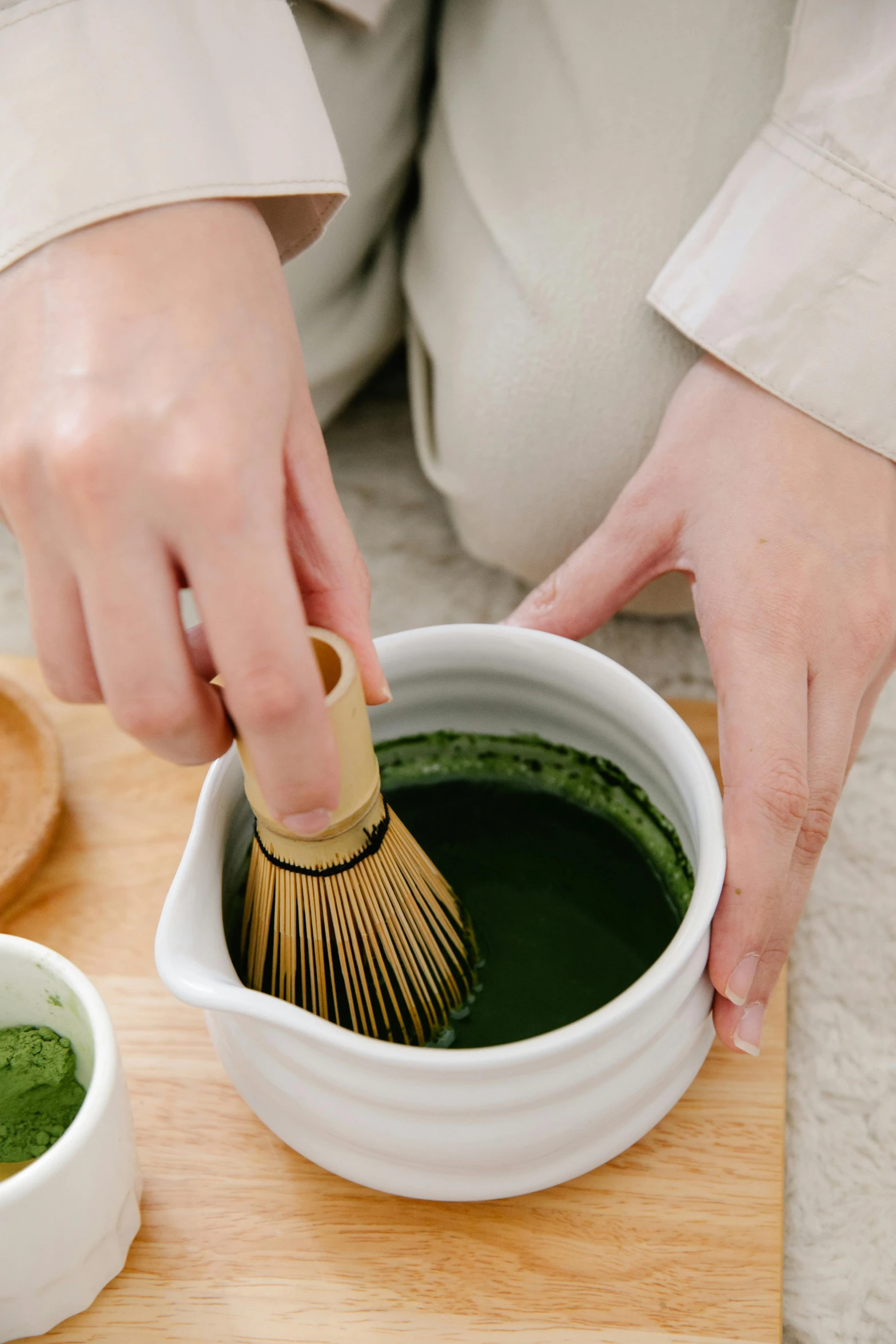 person with a wooden brush in a bowl filled with liquid