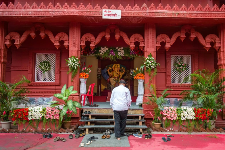 a man standing in front of a red house with flowers