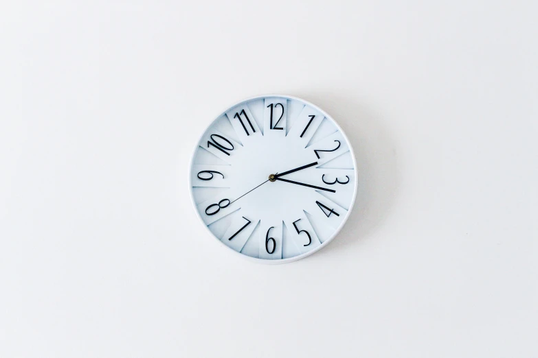 a white clock on the side of a wall with numerals