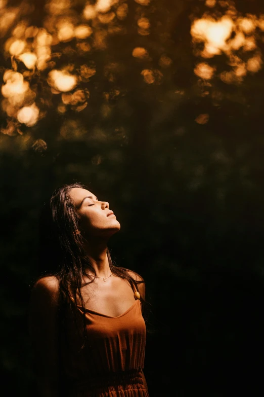 a woman standing in front of trees and sun