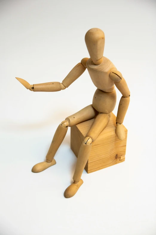 an unfinished wooden doll sits on top of a crate