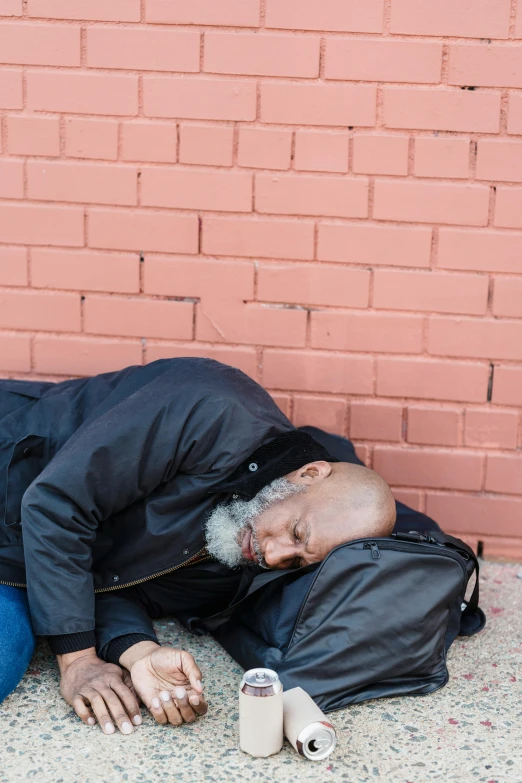 man sleeping on the ground with one hand in his pocket