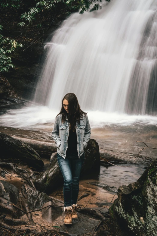 a woman stands near a waterfall by itself