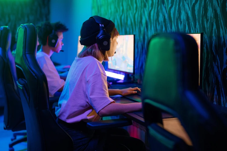 three people are using large monitors in a brightly lit area