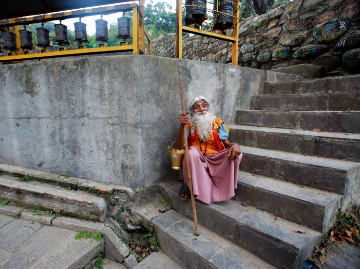 an old man sitting on the steps of a cemetery