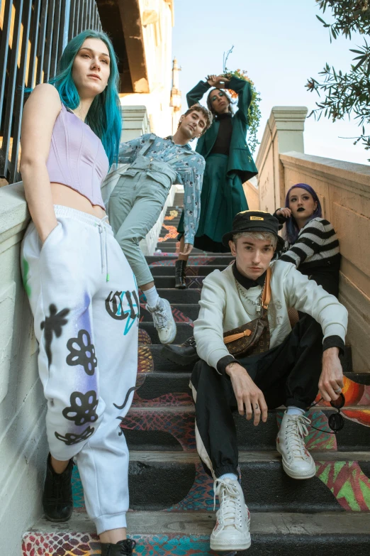 young men and women sitting on stairs and wearing clothes with graffiti