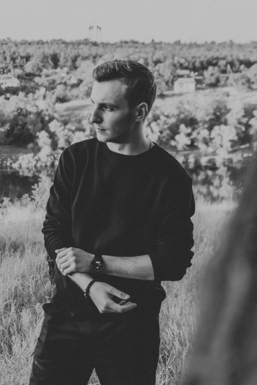 a young man standing in tall grass looking away