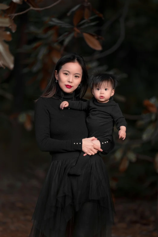 a woman holds her toddler girl in the fall leaves