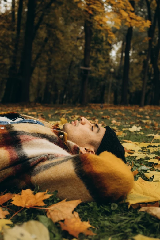 a man laying in the leaves near a tree