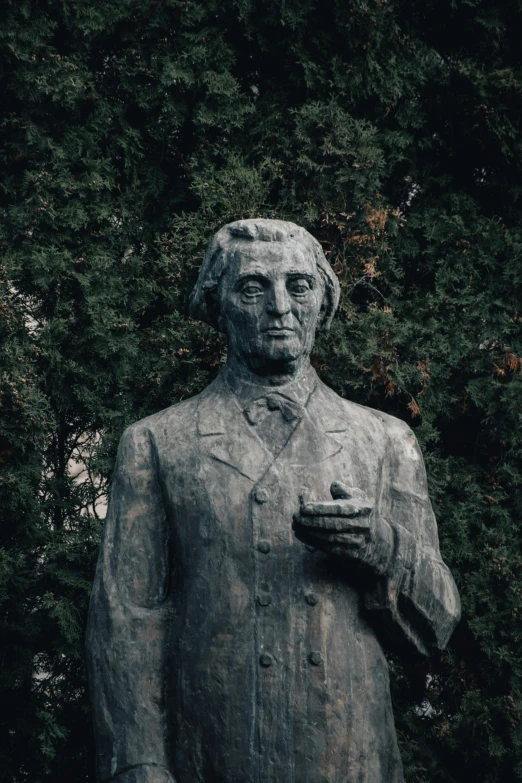 the statue in front of some trees is wearing a suit