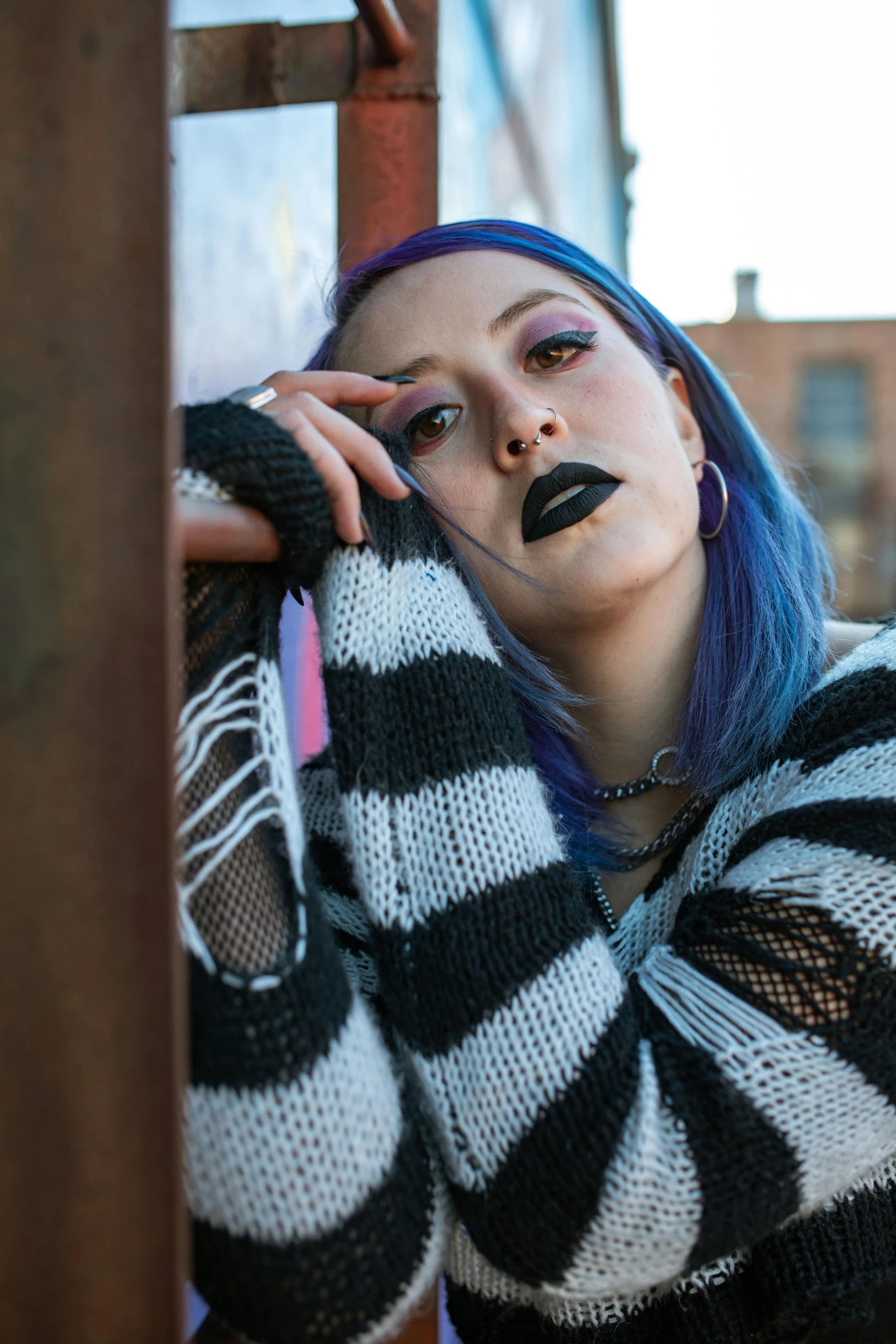 young woman with blue hair in striped sweater posing