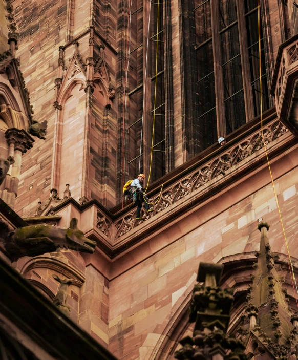 a man is hanging on the top of the building