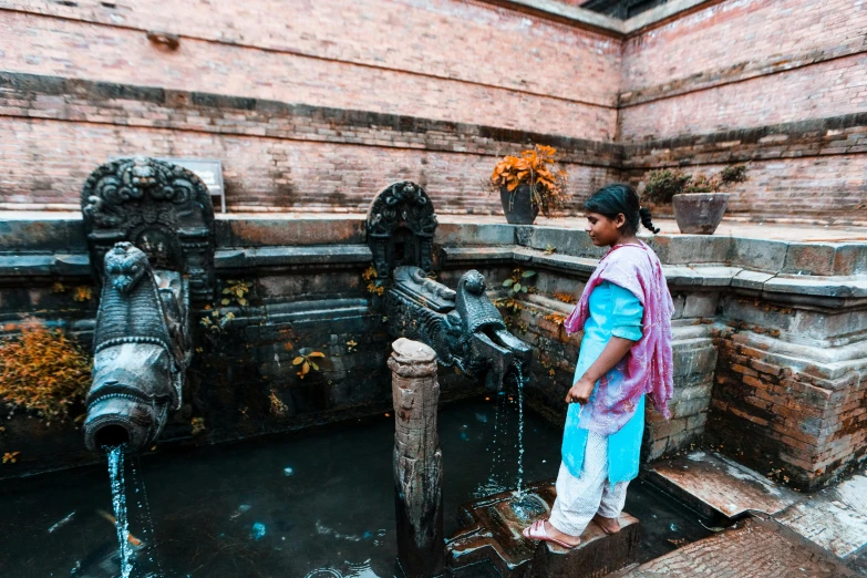 a woman standing in front of an ornate water fountain