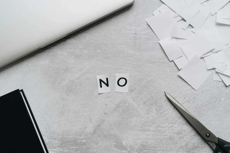 paper cut out to say no on a table next to computer and papers