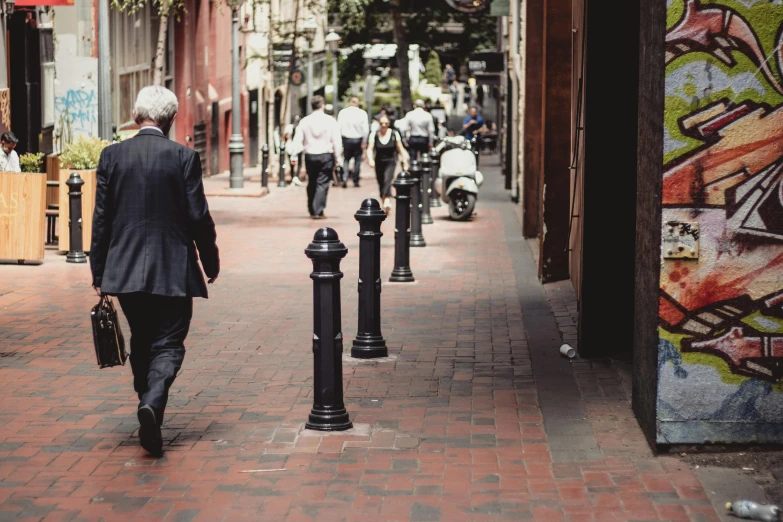 man in suit walking down sidewalk of alley