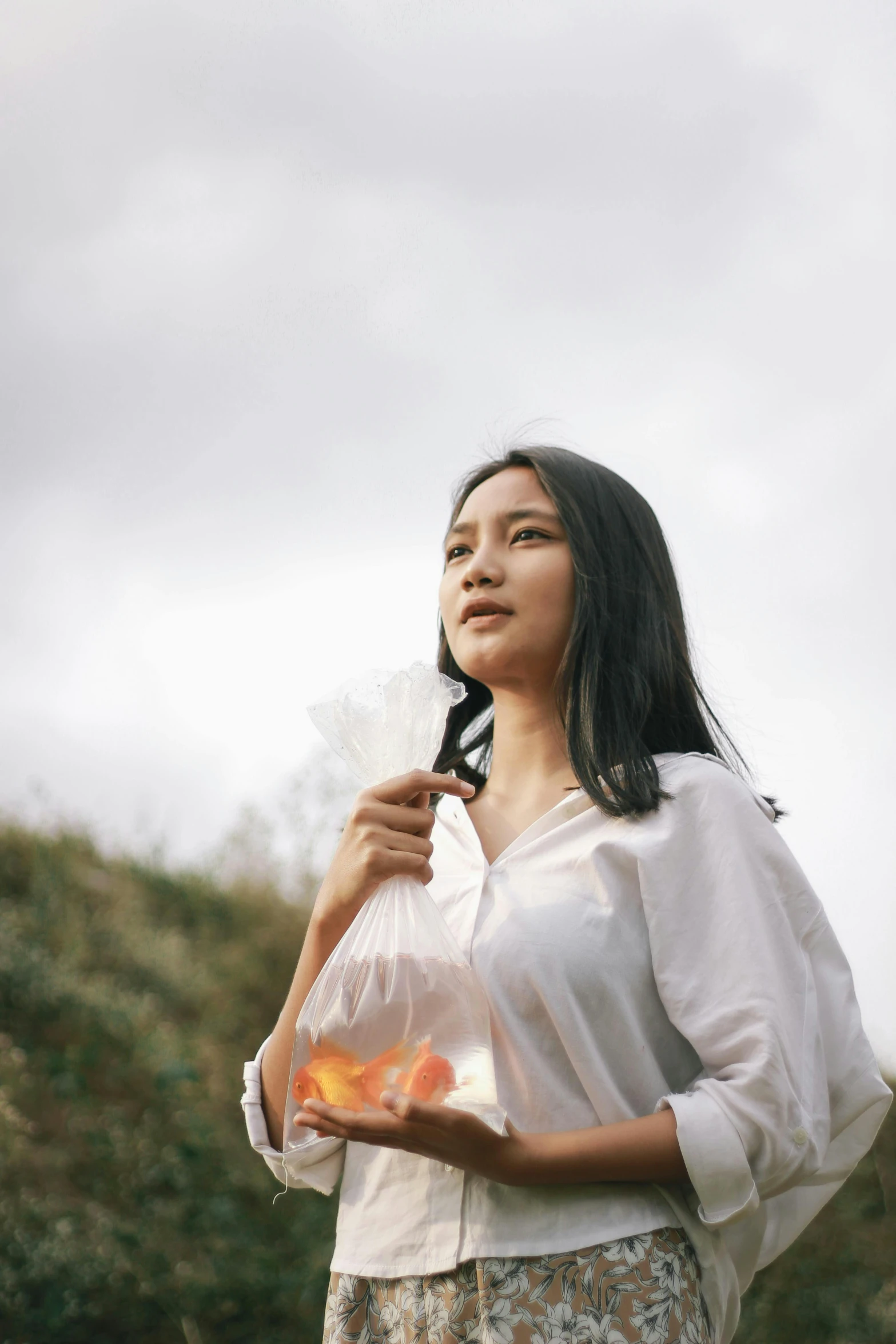 woman in dress standing in field holding an umbrella