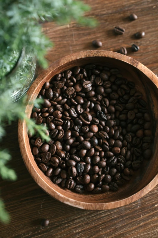 coffee beans in a wooden bowl sitting on a table