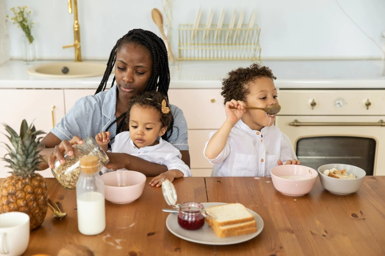 two s sit and eat food as an adult woman watches