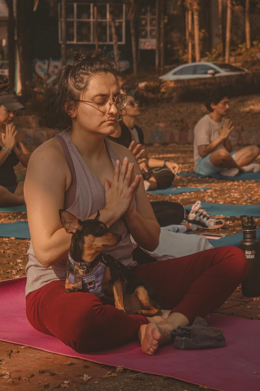 a woman is sitting with her dog and a yoga mat