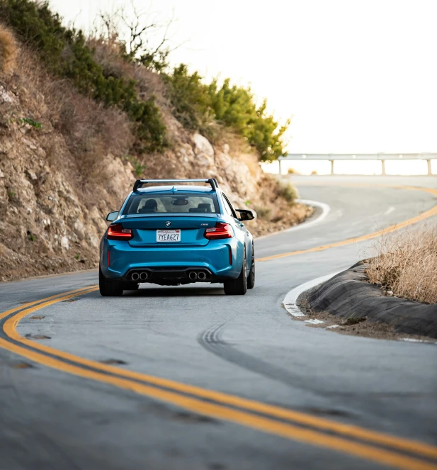 a blue car driving down the highway on a sunny day