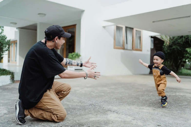 a man kneeling down holding his hands out to a child who is kneeling down