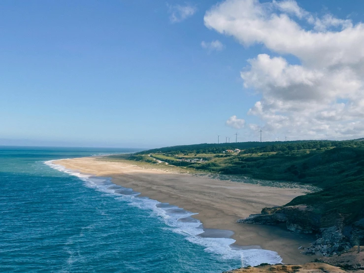 an expansive beach and a hill that is on the edge of the ocean