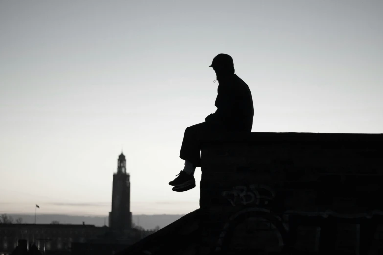 the silhouette of a man is sitting on the top of a building