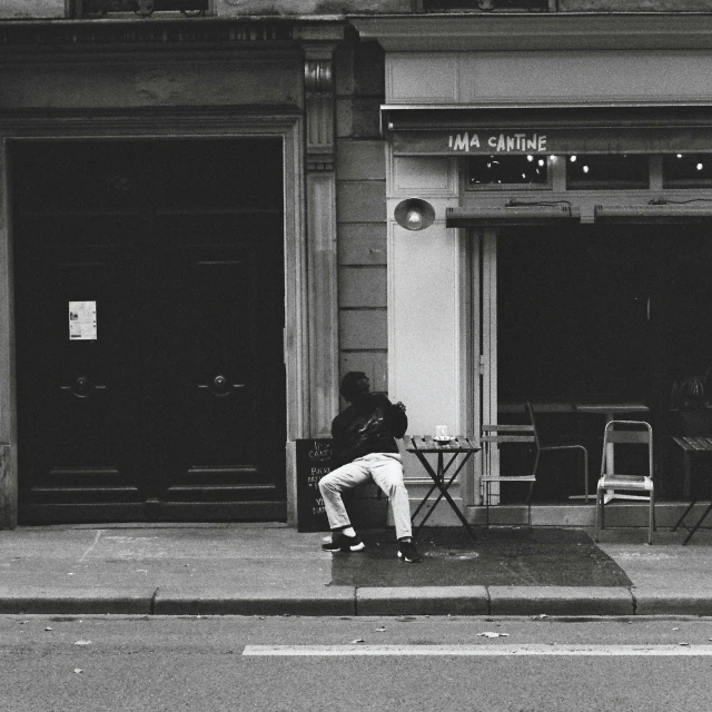 a person sitting at a table on the side walk