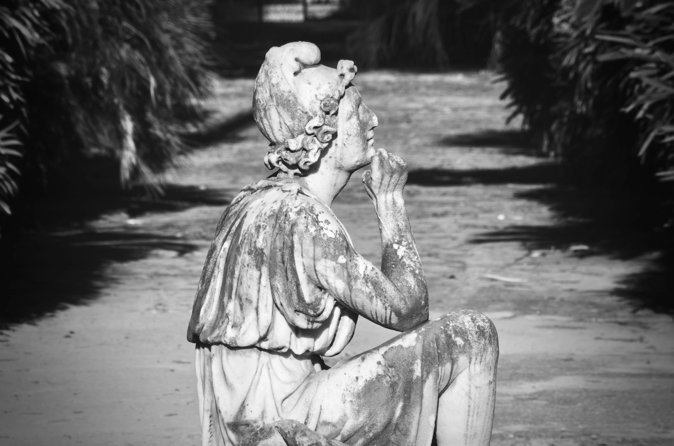 a statue is sitting on a road next to palm trees