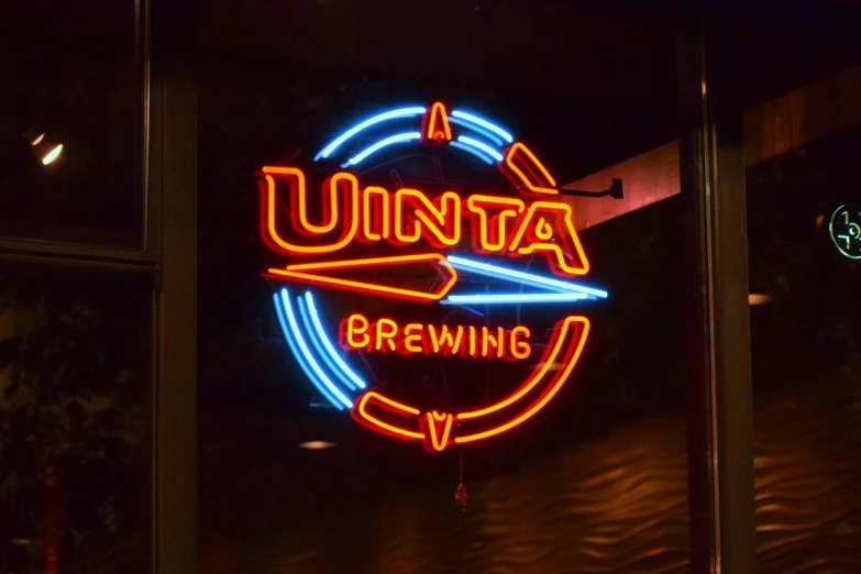 a neon sign for a beer in front of a dark room