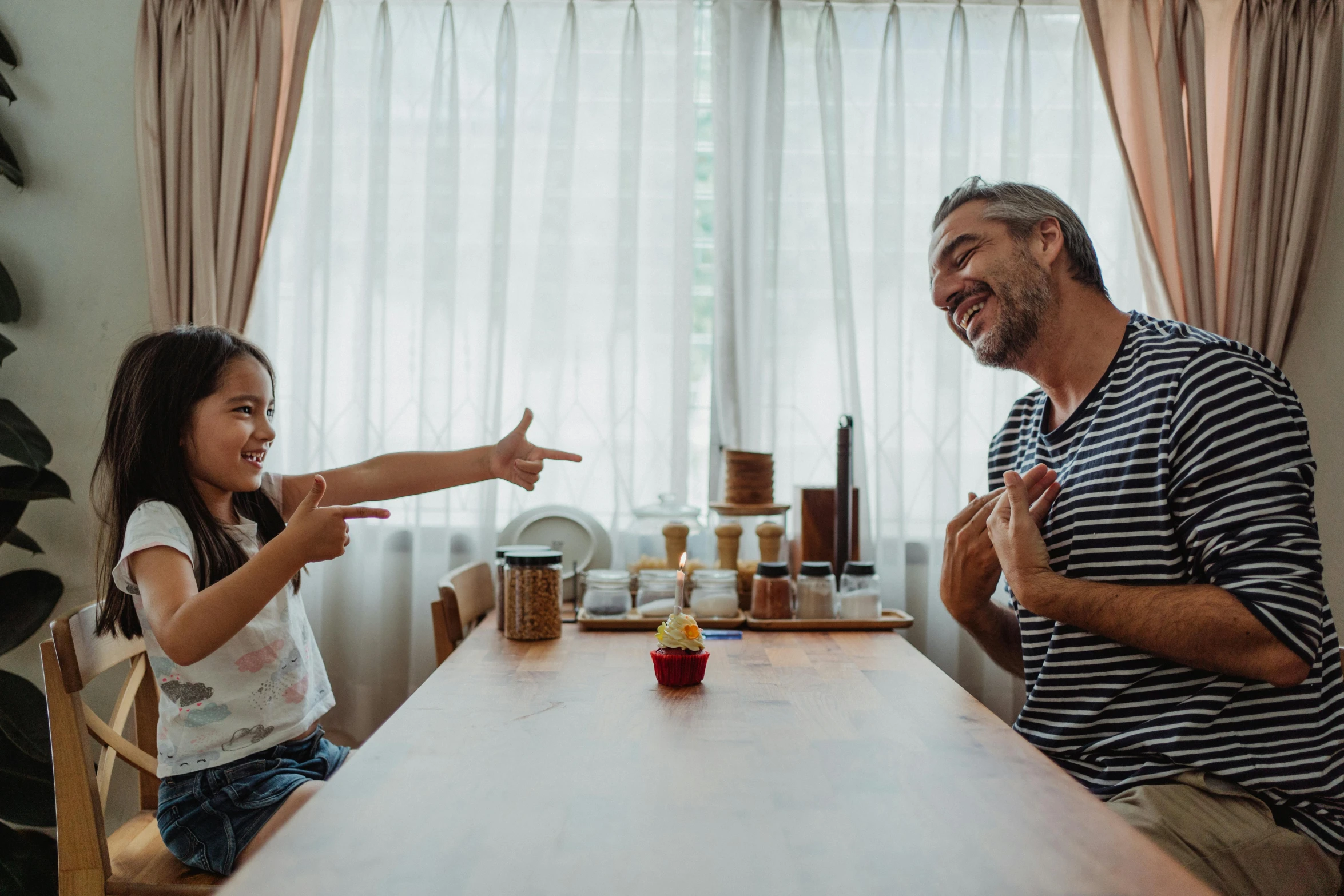 a man is smiling and pointing a finger toward a child at a table