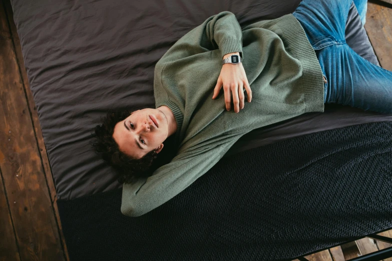 a man in green shirt laying on black bed