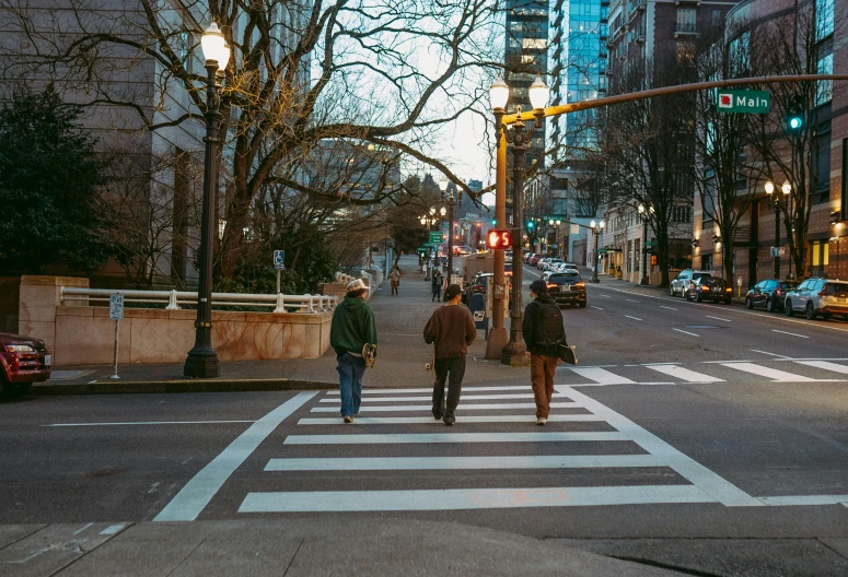 three people cross the street at a crosswalk