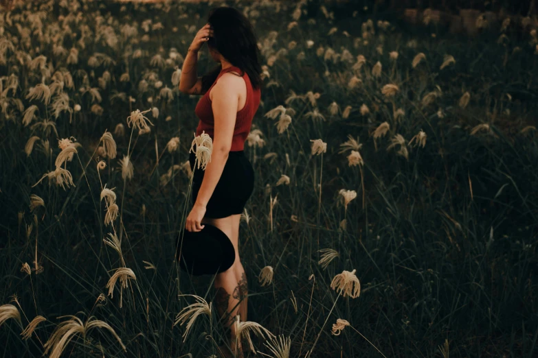 a woman walking through the tall grass while talking on her phone