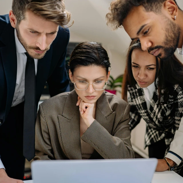 two women and a man looking at a laptop screen