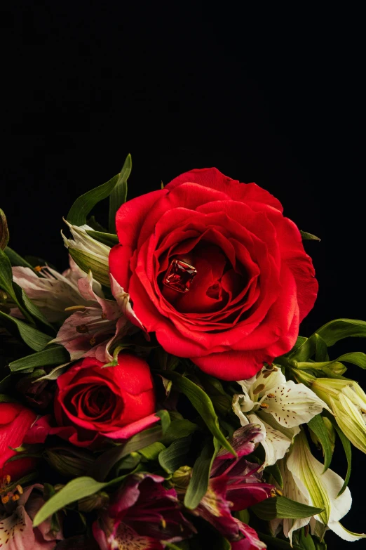 bouquet of red flowers with two engagement rings