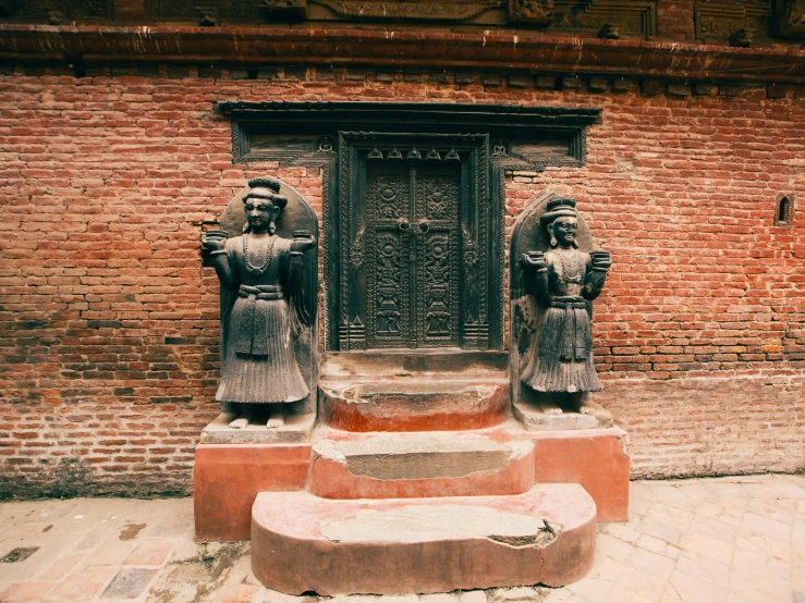 two stone statues stand near each other next to a door