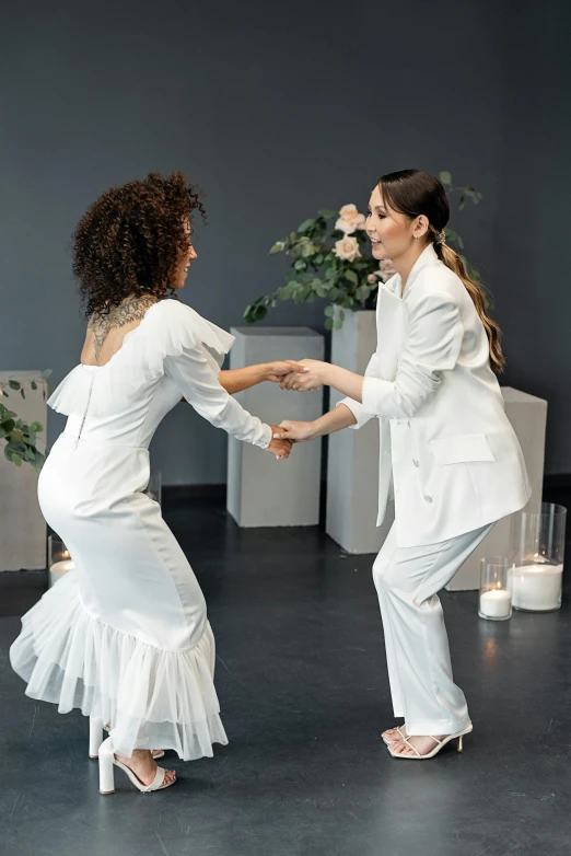 two people dressed in white dancing at a dance party