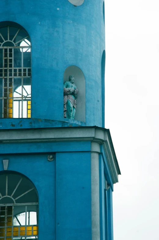 a clock tower with a statue standing on the top