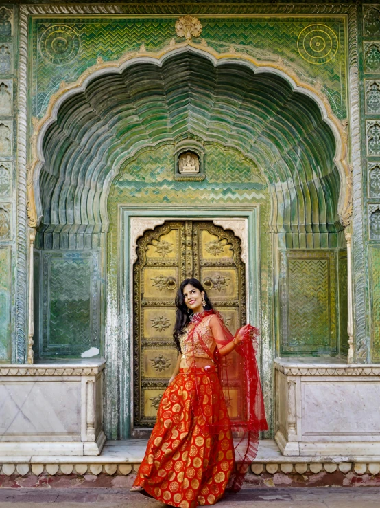 a woman in red sari standing outside of a building