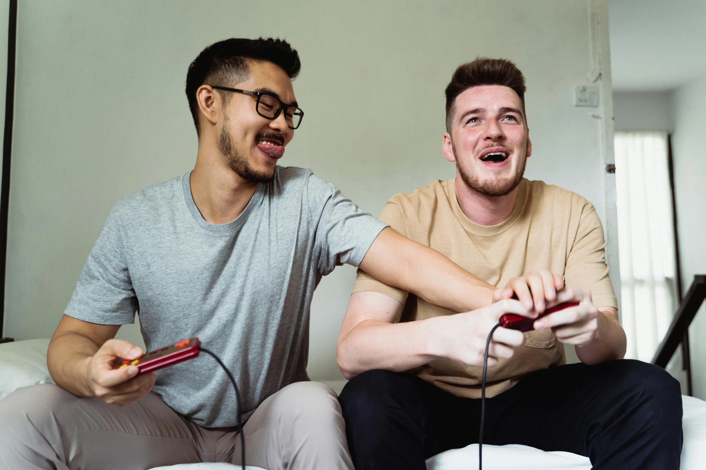 two men playing on nintendo wii while sitting on a couch