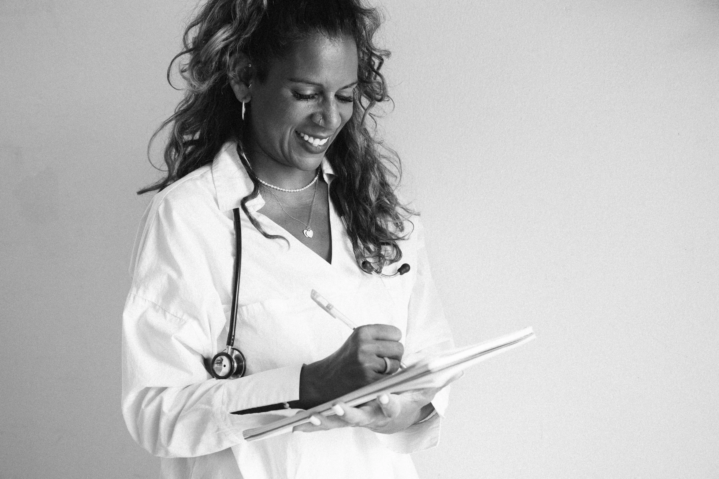 a woman in white shirt and stethoscope looking at a clipboard