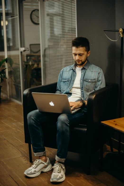 man sitting in chair working on laptop computer