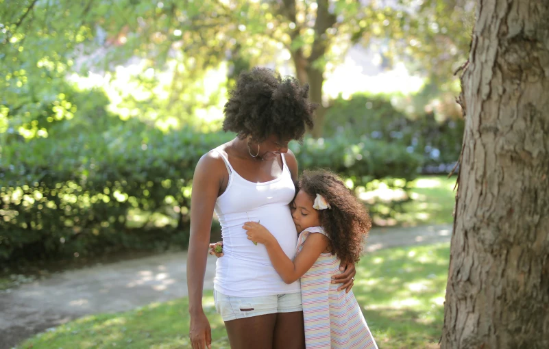 a mother and daughter hugging each other in the park