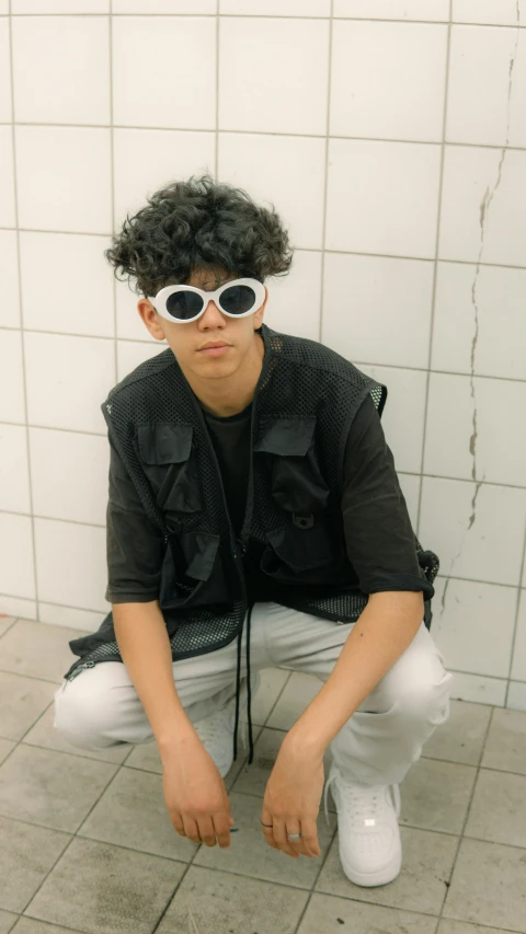 a man with black shirt and sunglasses sitting on a toilet